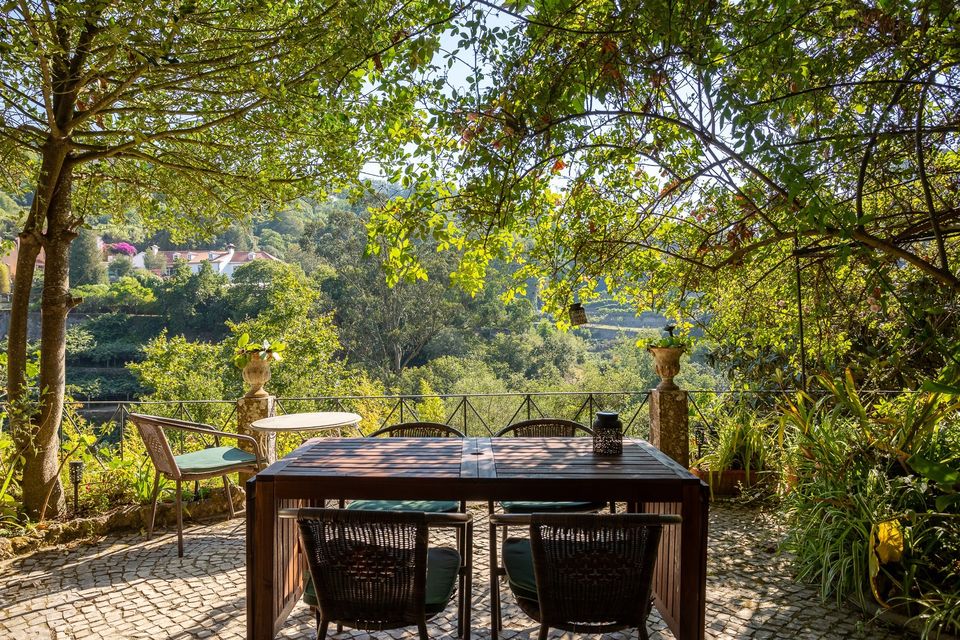 The long garden table set under the trees, with the terraced hillside and the Arraçário Valley opening up beyond it.