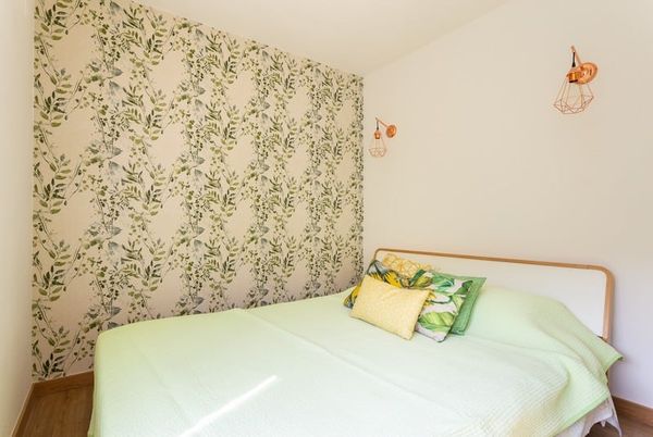 The Studio's queen bed against wallpaper of green leaves.