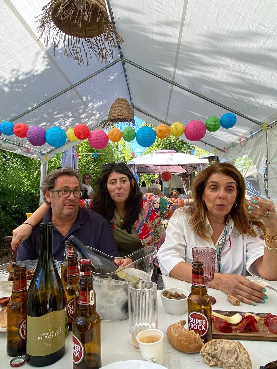 A celebration under a white marquee, with paper lanterns strung overhead and guests raising their glasses.