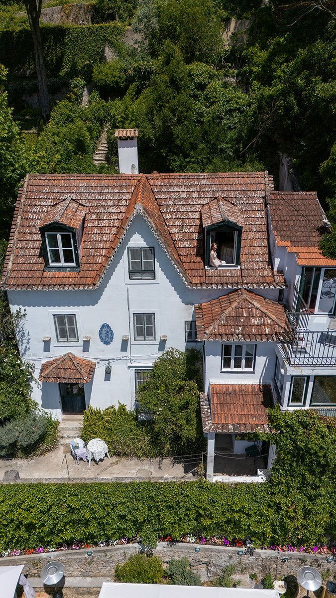 The house from above, its terracotta roofs and dormer windows set among the gardens, with the green of the valley all around it.